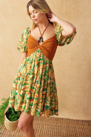 A crochet and print combination mini dress featuring crochet bodice with halter tie and beading, short puff sleeve and tiered skirt