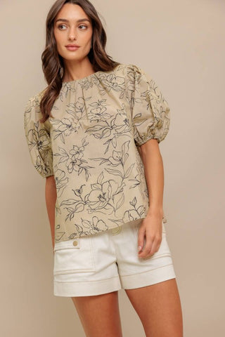 A printed woven top featuring round neckline, short puff sleeve and back neck tie closure