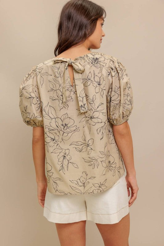 A printed woven top featuring round neckline, short puff sleeve and back neck tie closure