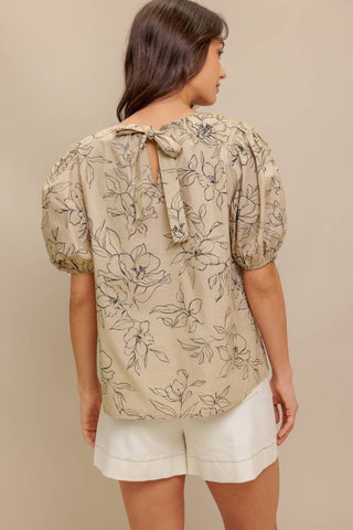 A printed woven top featuring round neckline, short puff sleeve and back neck tie closure
