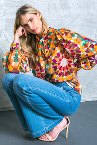 A printed woven top featuring high neckline with tie and long sleeve with cuff