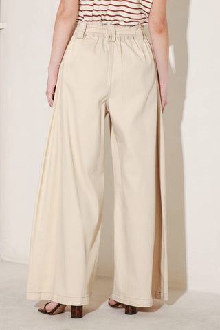 A solid woven pant featuring front closure, elastic waist with tie, pockets and wide leg.
