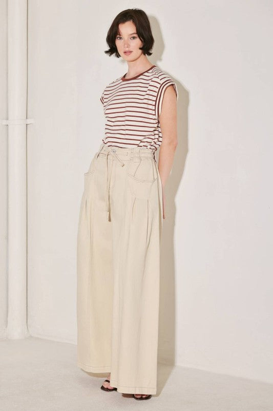 A solid woven pant featuring front closure, elastic waist with tie, pockets and wide leg.