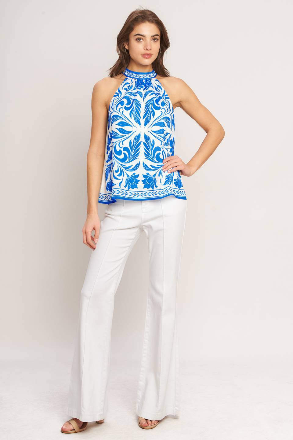A printed woven top featuring halter neckline with back neck tie and sleeveless