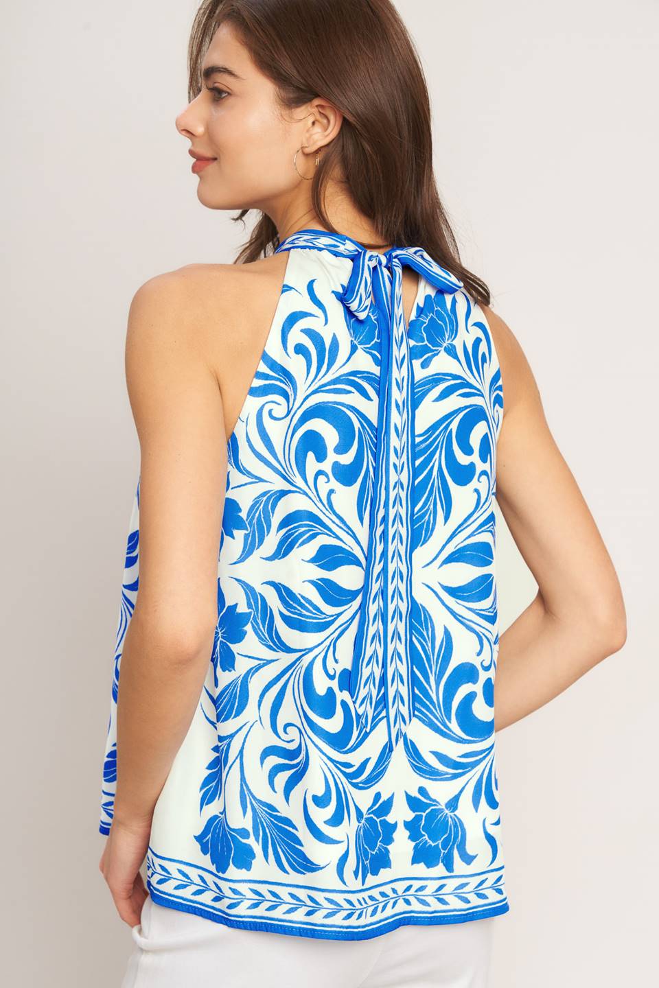 A printed woven top featuring halter neckline with back neck tie and sleeveless
