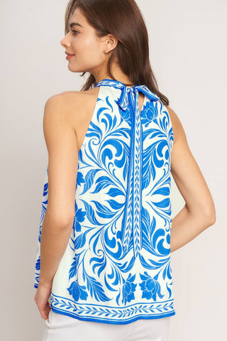 A printed woven top featuring halter neckline with back neck tie and sleeveless