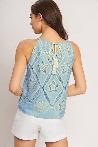A woven embroidered top with halter neckline with back tie/tassel
