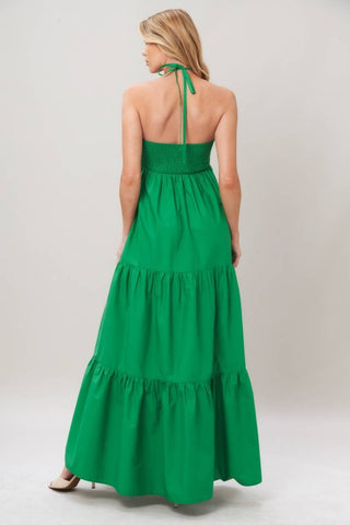 A solid woven maxi dress featuring shirred twist front bodice, tier skirt, back neck tie and smocked back bodice