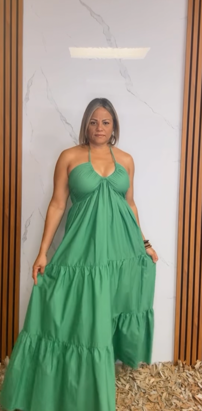A solid woven maxi dress featuring shirred twist front bodice, tier skirt, back neck tie and smocked back bodice