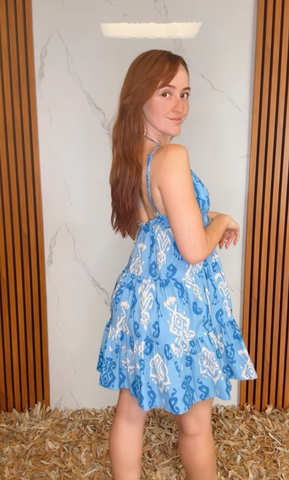 A printed woven mini dress featuring cami top, elastic empire, tier skirt and bare back with back neck tie