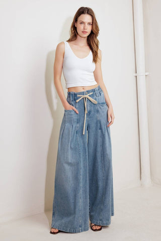 A washed denim pant featuring front closure, elasticized waist with contrasting tie, side pocket and wide leg