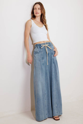 A washed denim pant featuring front closure, elasticized waist with contrasting tie, side pocket and wide leg