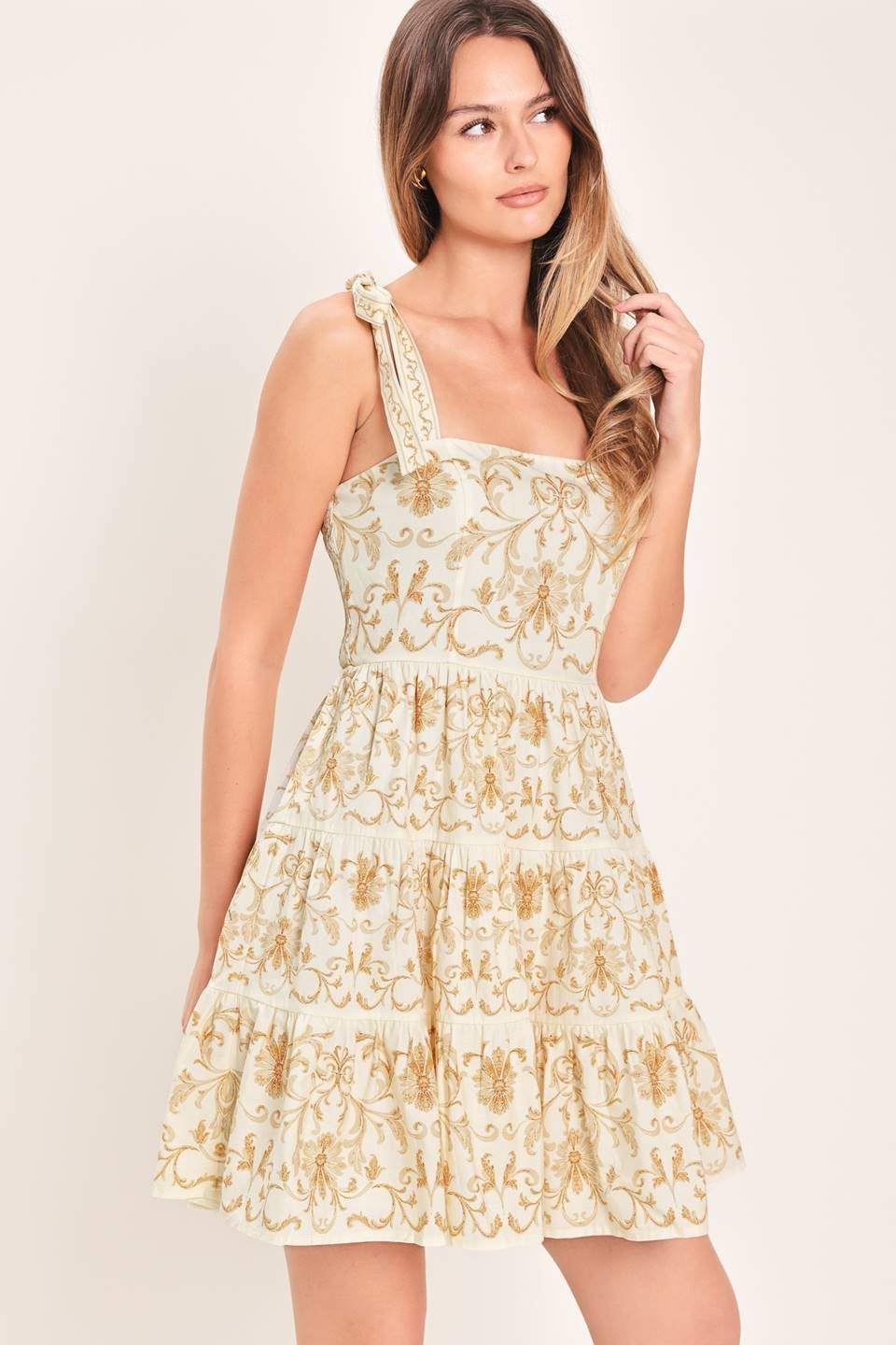 A printed woven mini dress featuring straight neckline, shoulder ties, tier skirt and smocked back bodice