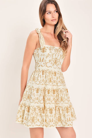 A printed woven mini dress featuring straight neckline, shoulder ties, tier skirt and smocked back bodice