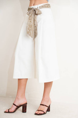 A solid woven culotte pant featuring front closure, pockets and printed sash