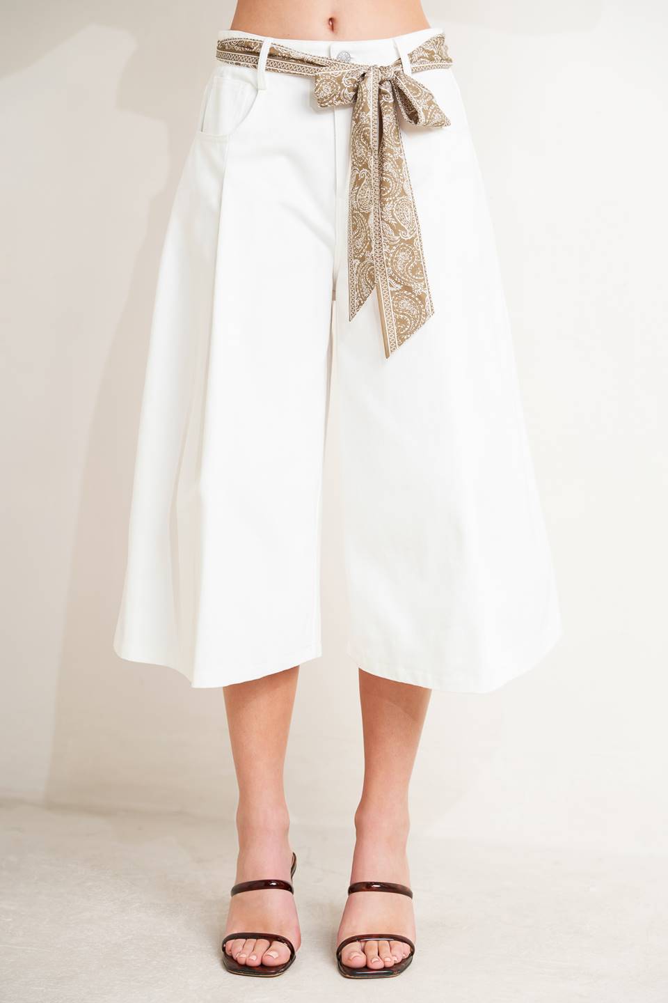 A solid woven culotte pant featuring front closure, pockets and printed sash