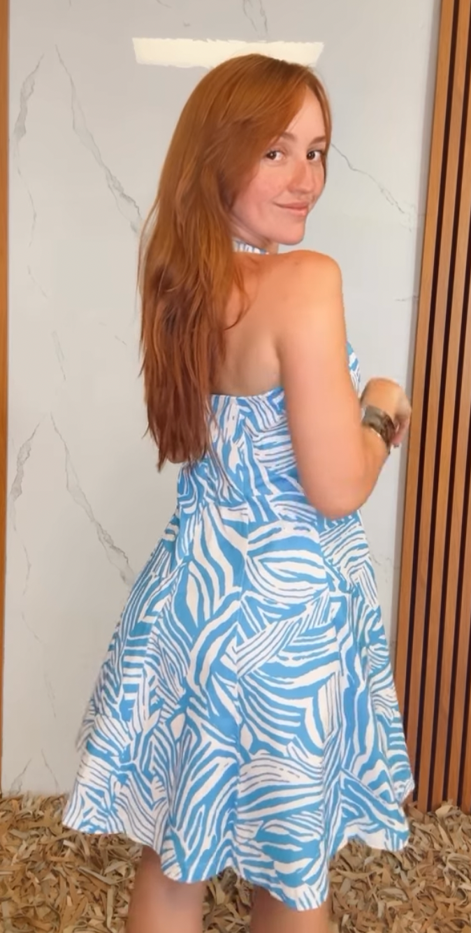 A printed woven mini dress featuring Queen Anne halter neckline, full circle skirt, bare back and zipper closure