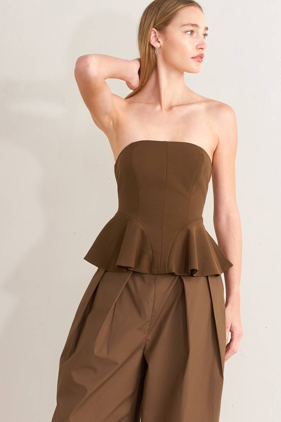 A solid woven tube top with peplum and back zipper closure