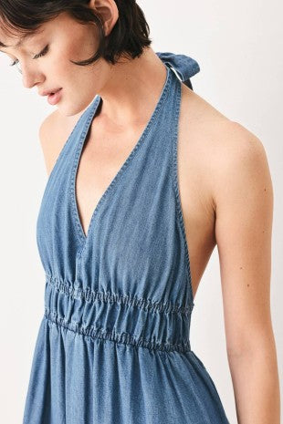 A washed denim midi dress featuring halter neckline, elastic waist, tier skirt, bare back with tie