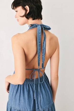 A washed denim midi dress featuring halter neckline, elastic waist, tier skirt, bare back with tie