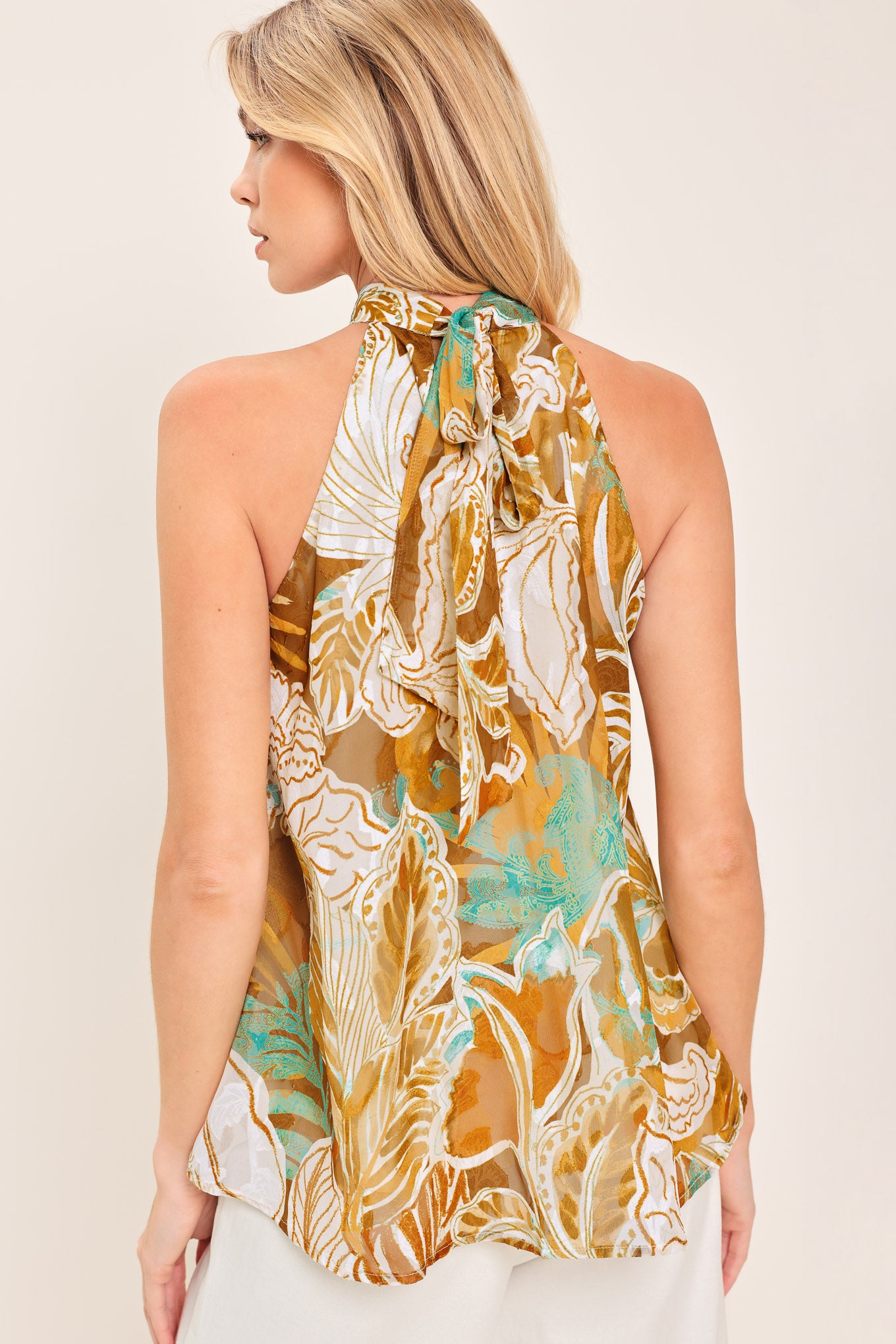 A woven jacquard printed top with halter neckline with back neck tie.