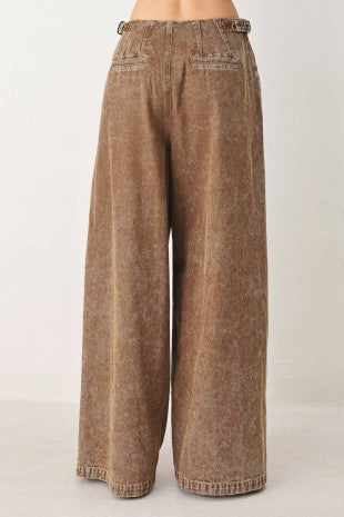 A washed denim pant featuring front closure, pockets and side buckle detail at waist