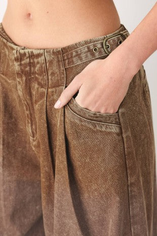 A washed denim pant featuring front closure, pockets and side buckle detail at waist