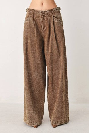 A washed denim pant featuring front closure, pockets and side buckle detail at waist