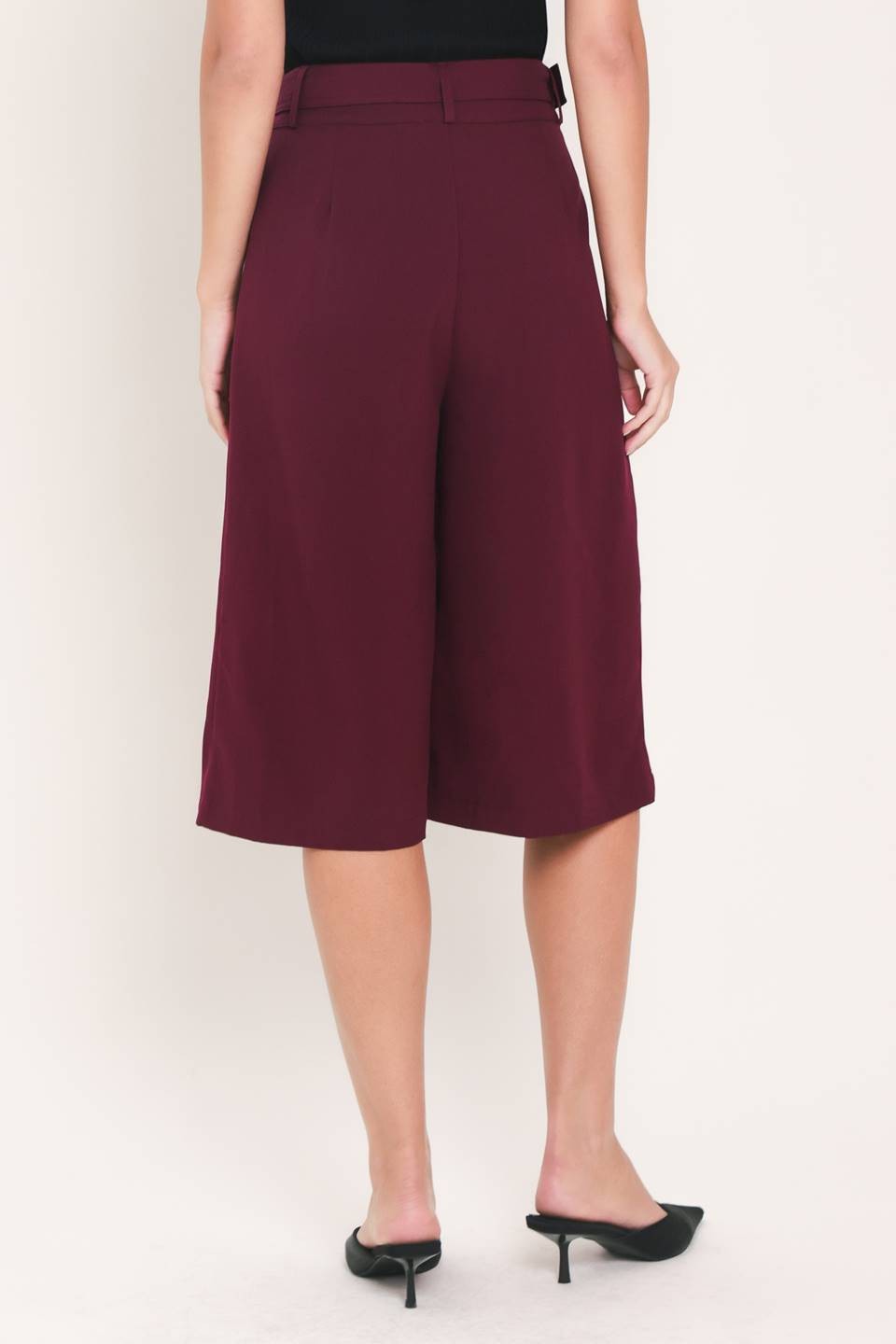 A solid woven culotte pant with buckle belt and front closure