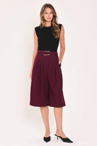 A solid woven culotte pant with buckle belt and front closure