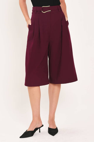 A solid woven culotte pant with buckle belt and front closure