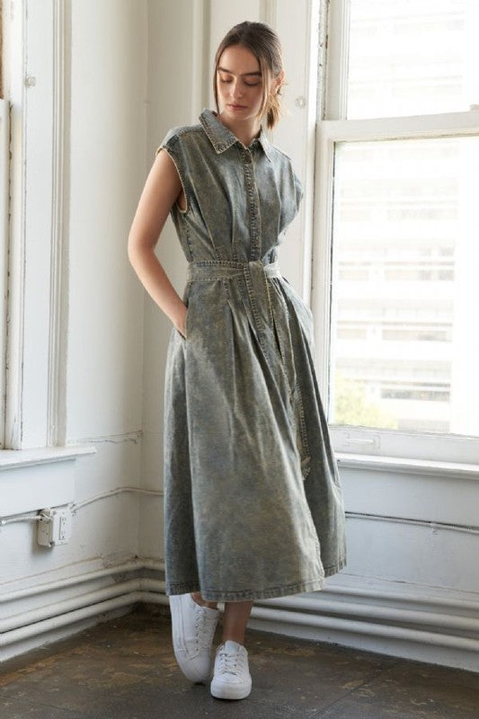 An overdyed denim midi dress featuring shirt collar, sleeveless, button down, self sash belt and full skirt