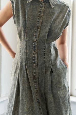 An overdyed denim midi dress featuring shirt collar, sleeveless, button down, self sash belt and full skirt