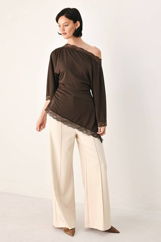 A solid knit top with boat neckline, bell sleeve, asymmetrical hem and lace edge