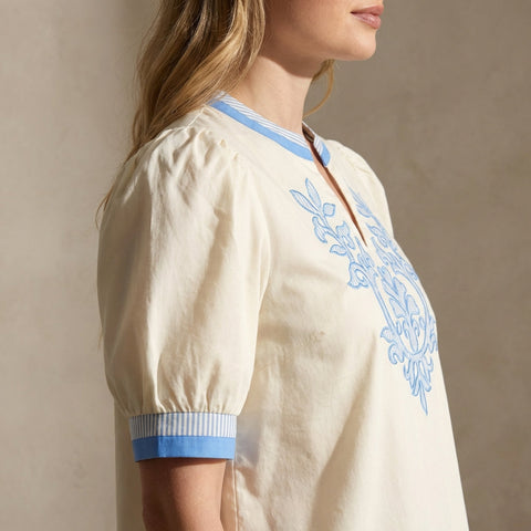 High-resolution side profile of embroidered top on mannequin in minimalistic studio with focused lighting.