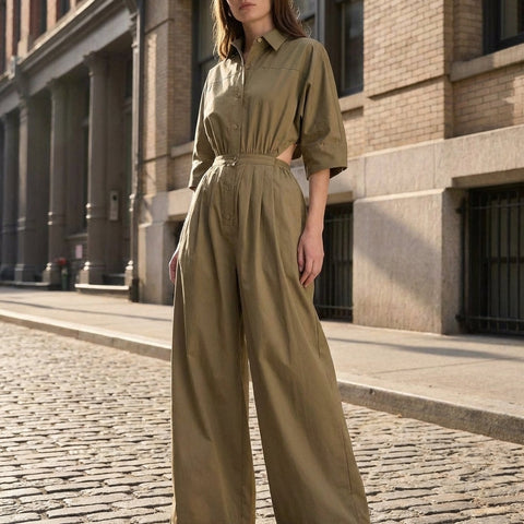 Full-body view of a model in a utility style jumpsuit with wide-leg silhouette in an outdoor city setting.